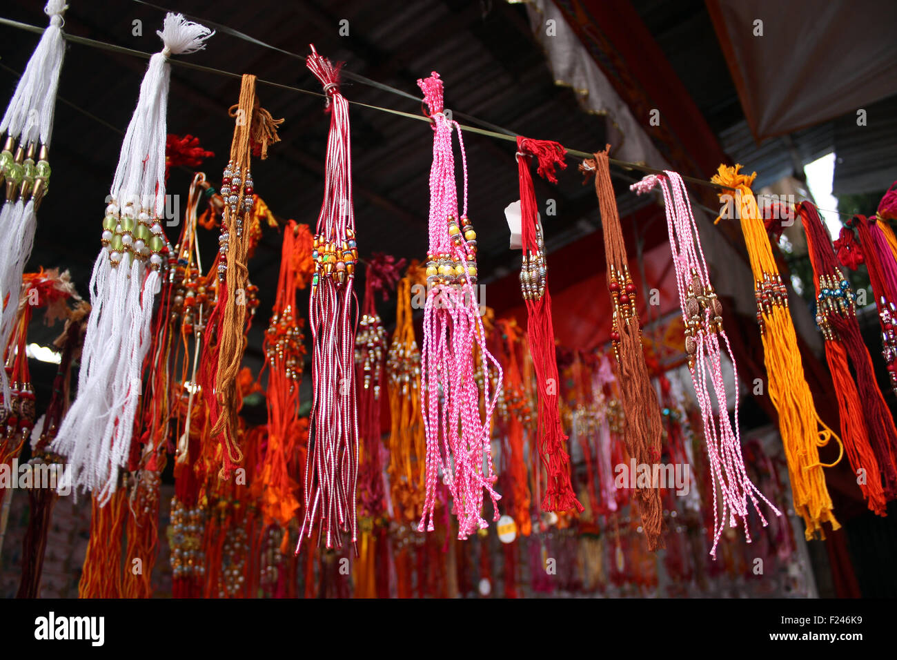 Rakhis colorati utilizzati nella tradizionale festa indiana, appeso per la vendita in una strada laterale-shop. Foto Stock