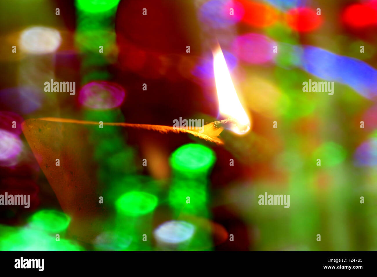 Un tradizionale di terracotta Diwali illuminata dietro una stringa di colorati delle lampadine in blur Foto Stock