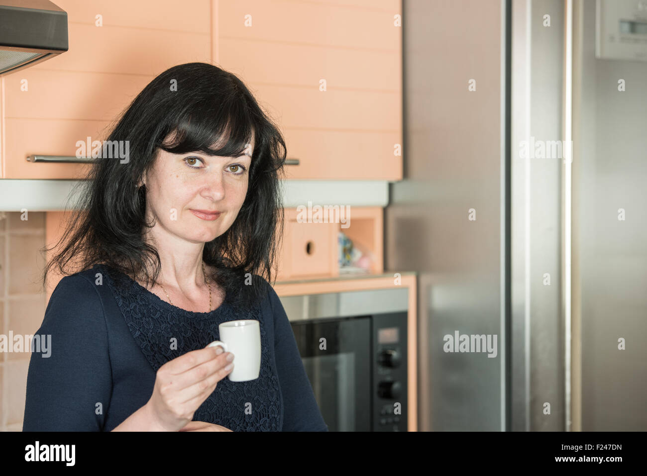 Donna sorridente indossando abiti di bere il caffè al mattino Foto Stock Donna sorridente indossando abiti di bere il caffè al mattino Foto Stock