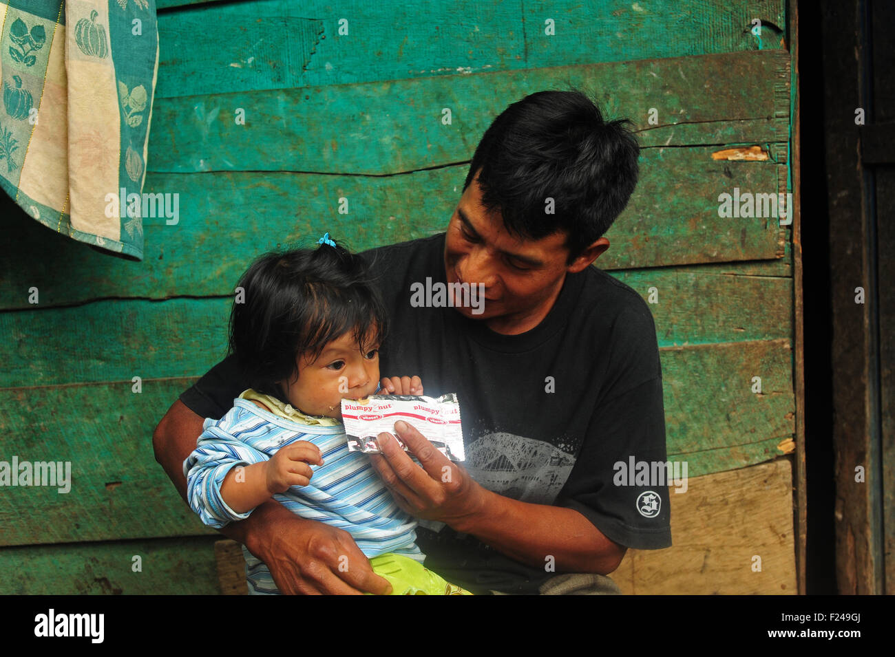 Guatemala, San Cristobal, bambino seduto sul ginocchio del padre e mangiare il dado di plumpy (Adolfo Cal Lem 35 e Aracely Noemi Cal Cap 1 Anno 3 mesi) Foto Stock