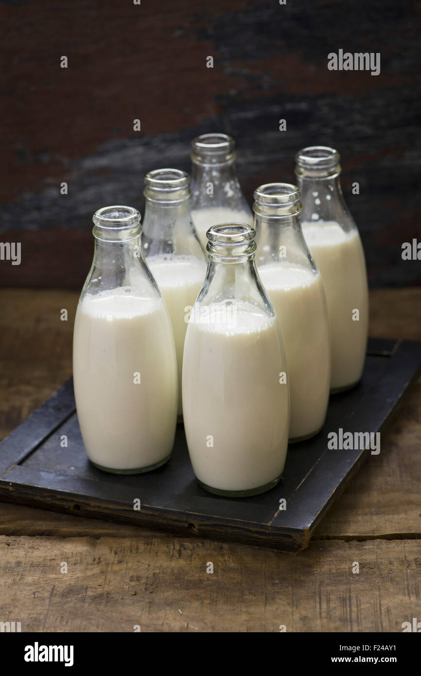 Latte in bottiglie su sfondo di legno Foto Stock