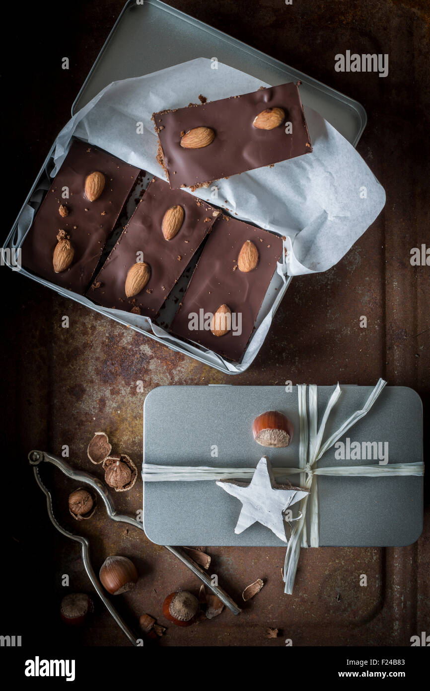 Gingerbead con ricchi di cioccolato e mandorle in aprire casella di argento e una scatola avvolto con nastro. Vista superiore Foto Stock