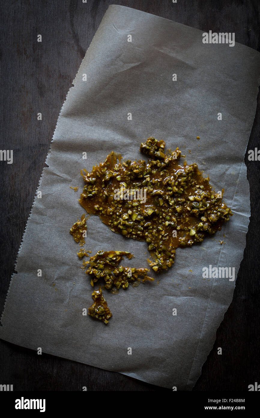 Il pistacchio crunch su un foglio di carta da forno sul tavolo di legno alto. Vista superiore Foto Stock