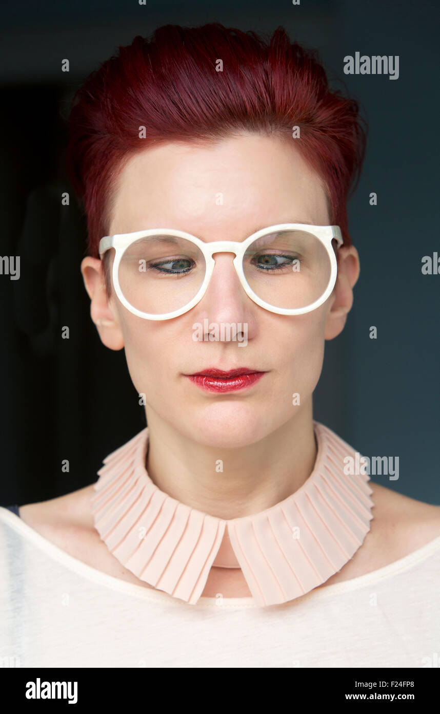 Ritratto di bella i capelli rossi donna che indossa gli occhiali di colore bianco e con gli occhi incrociati Foto Stock