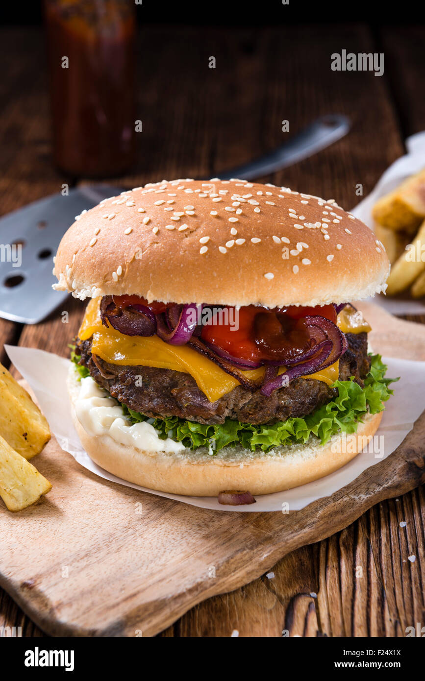 In casa hamburger di manzo con formaggio e chip su sfondo di legno Foto Stock