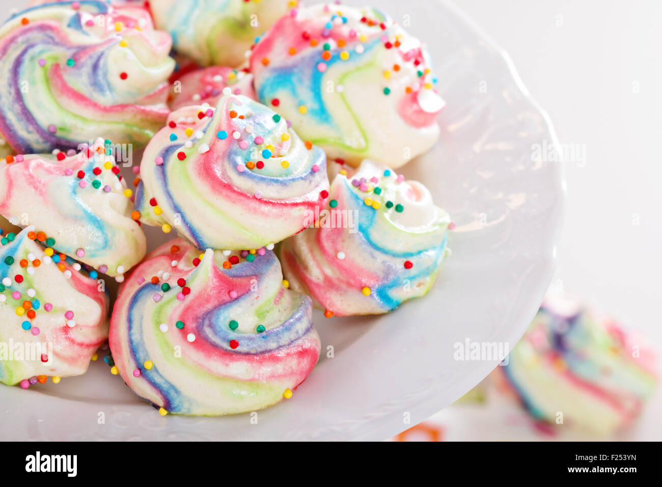 Meringhe colorate dipinte di colori arcobaleno con un pizzico Foto Stock