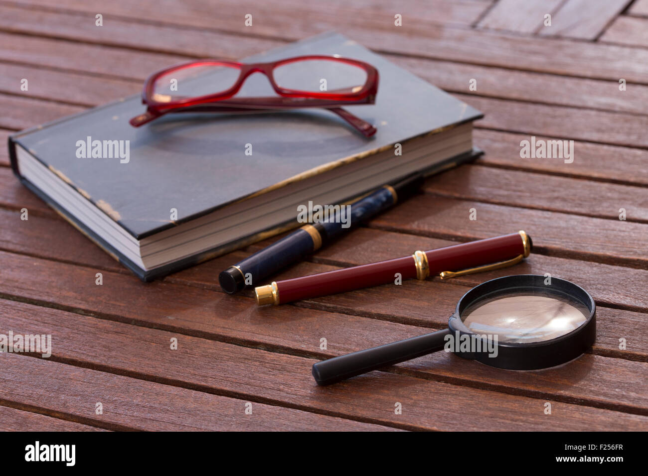 Prenota e occhiali e penne a una tabella Foto Stock