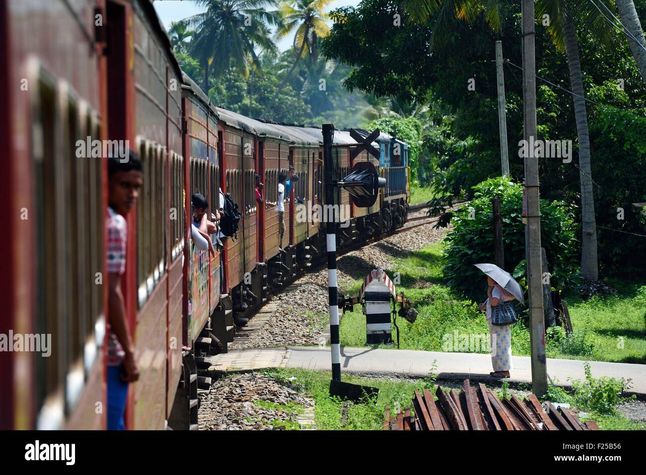 Sri Lanka, della provincia meridionale, in treno da Colombo a Galle, passeggeri appesi sulle porte verso Boossa Foto Stock