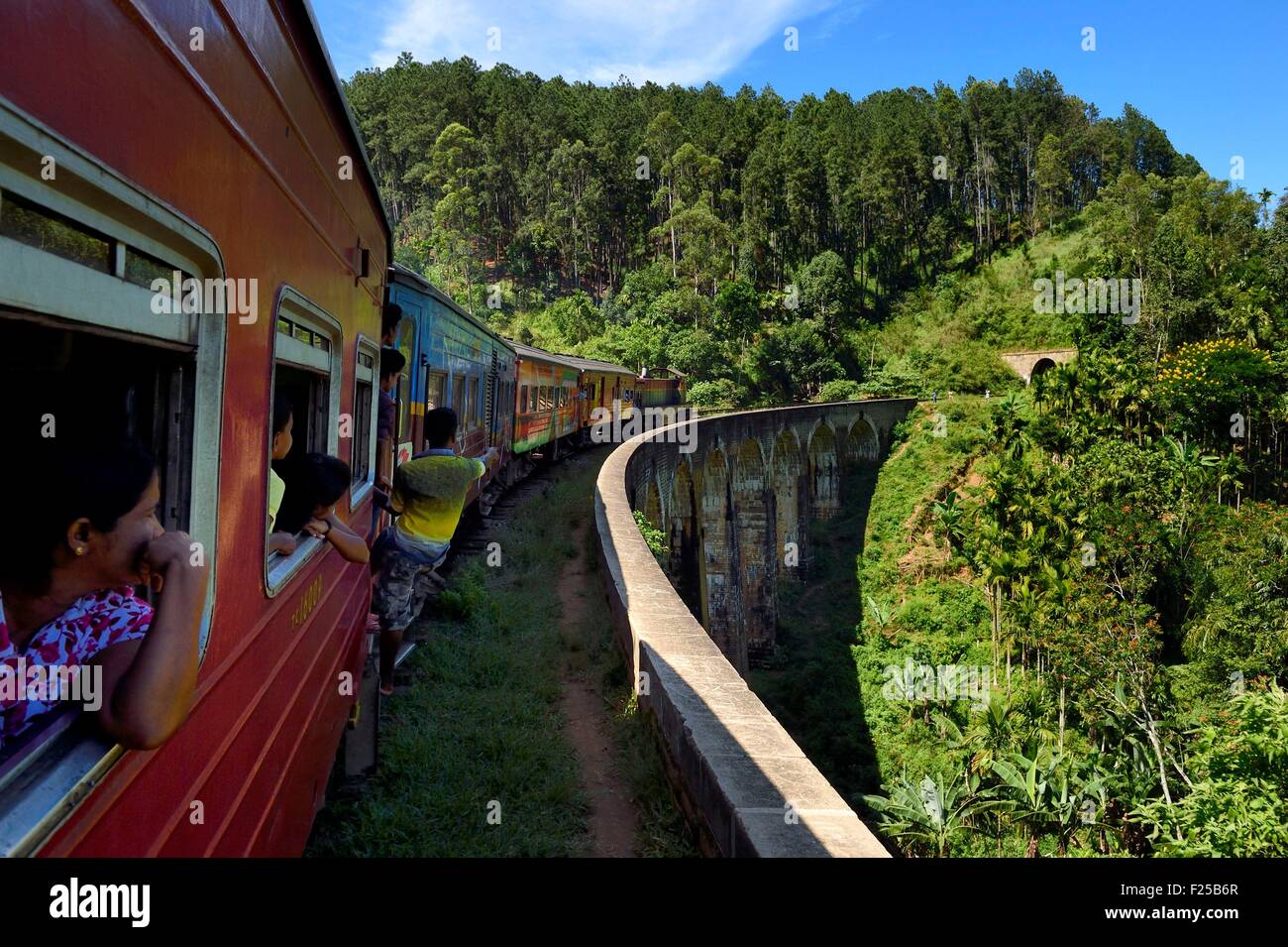 Sri Lanka, provincia di Uva, treno sulla linea ferroviaria che passa attraverso il tè crescente hill country tra Badulla e Ella, nove archi ponte accanto ad Ella, passeggeri appeso sulla porta Foto Stock