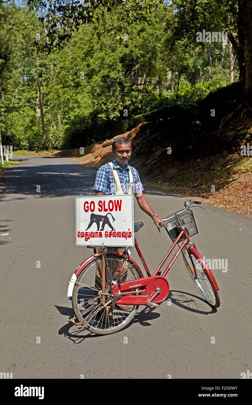 India, Tamil Nadu, Anaimalai Mountain Range (Nilgiri Hills), il ciclista con un cartello di avvertimento di automobilisti un possibile passaggio fauna selvatica in questo caso scimmie :Lion-coda Macaque (Macaca silenus), o il Wanderoo, Il lion-coda Macaque si colloca tra il ra Foto Stock