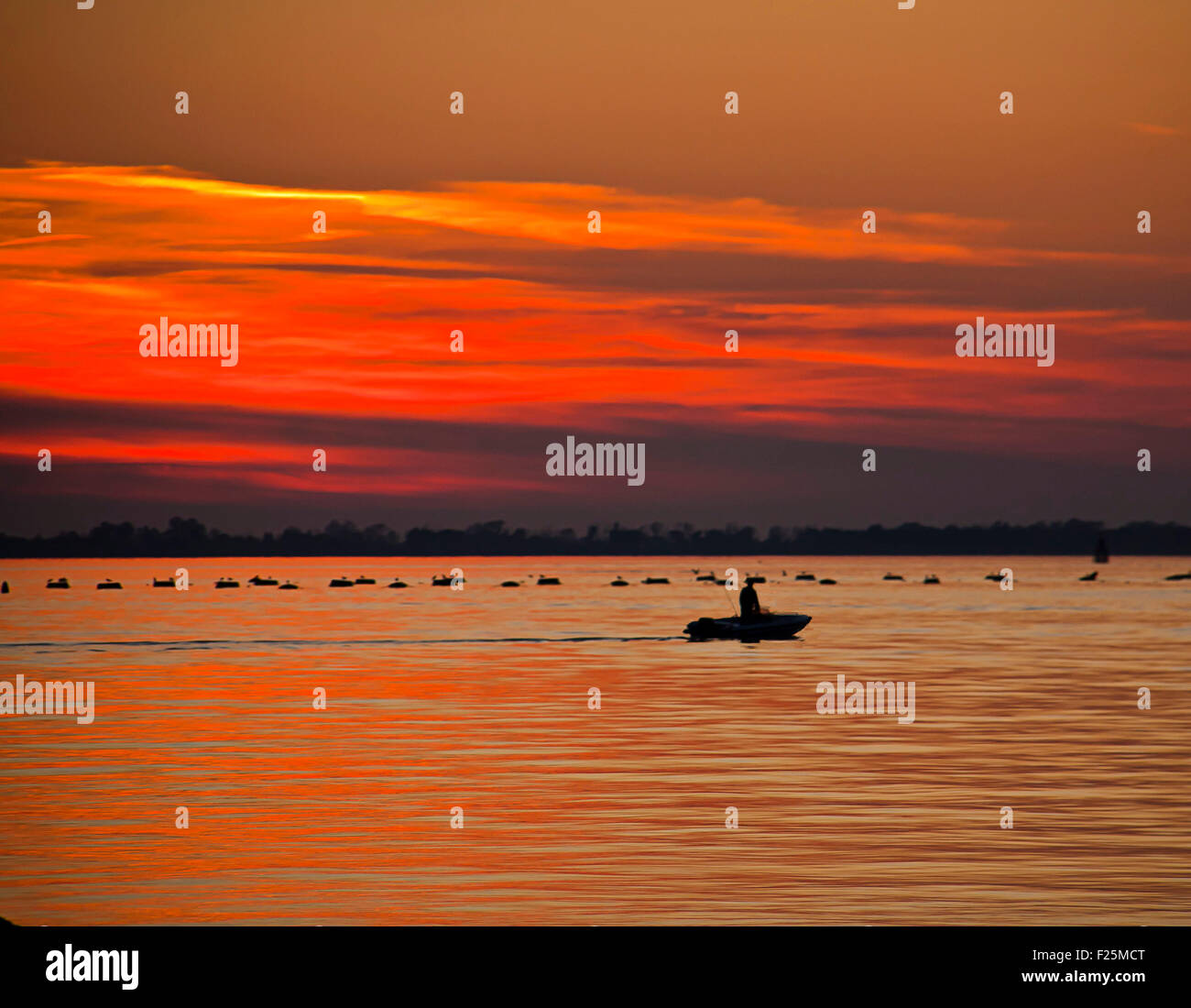 Rosso tramonto sul mare con silhouette di fisher sulla barca e agricoltura di shell su un tramonto rosso Foto Stock