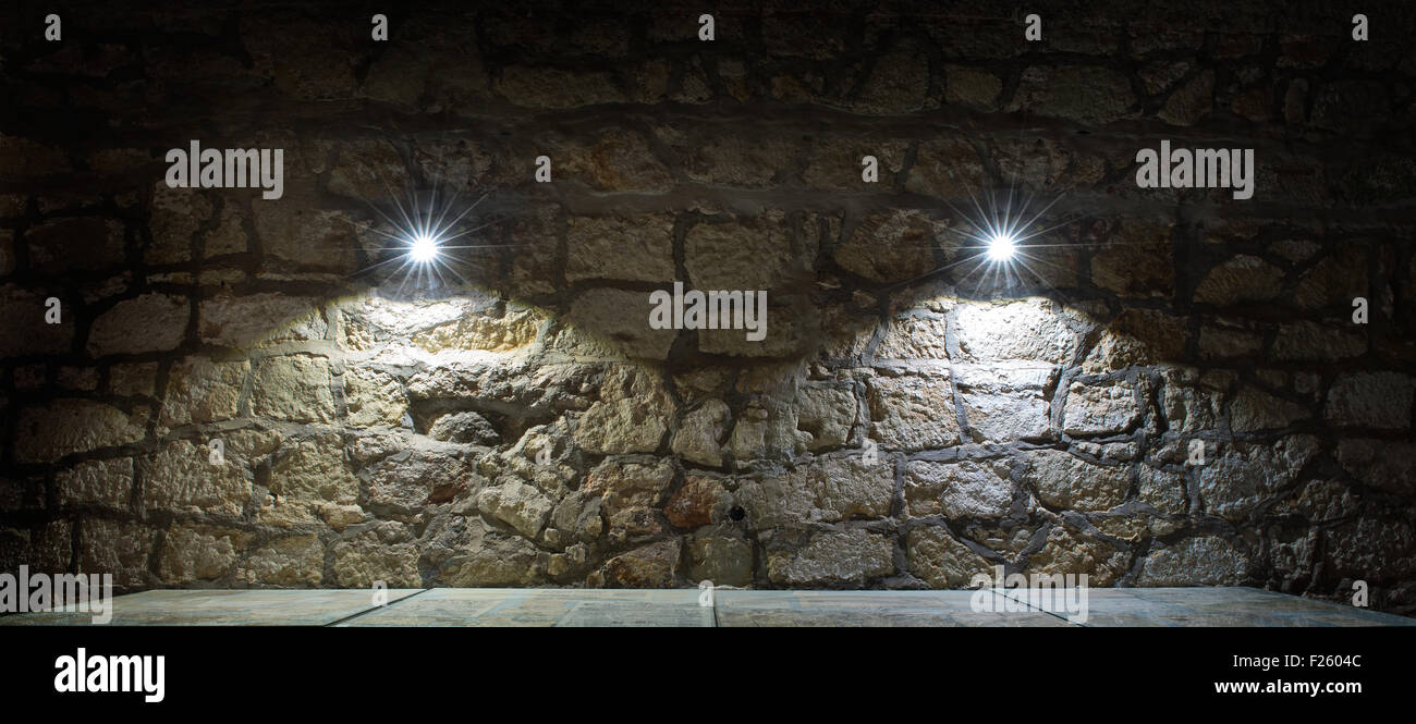 Muro di pietra e una tavola illuminata due lampade Foto Stock