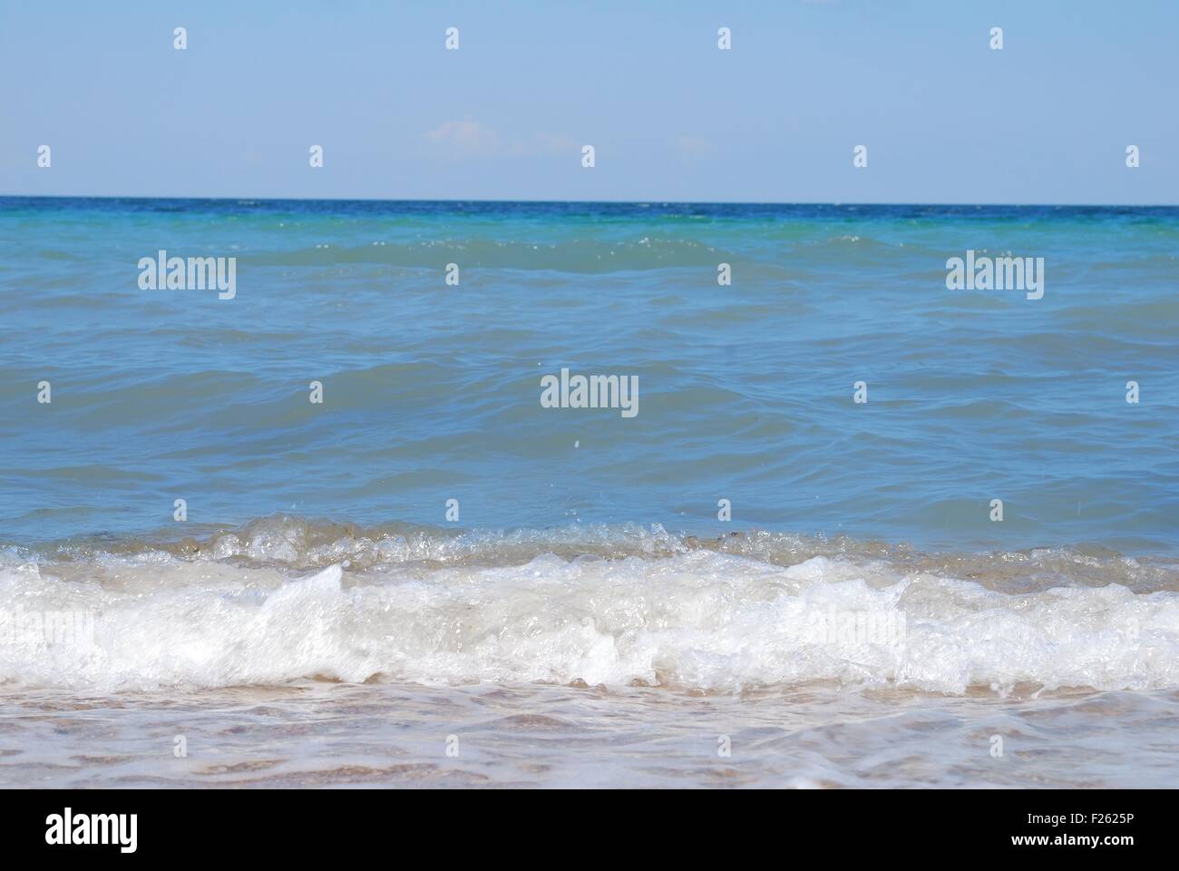 Le onde del mare con la schiuma sulla riva Foto Stock