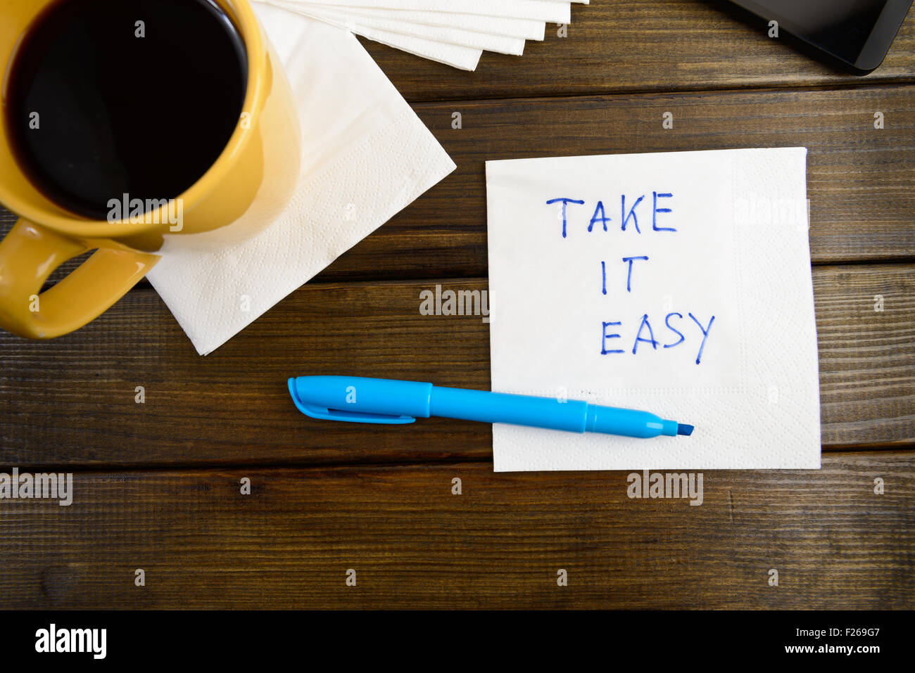 Take it easy - scrittura su un tovagliolo con una tazza di caffè Foto Stock