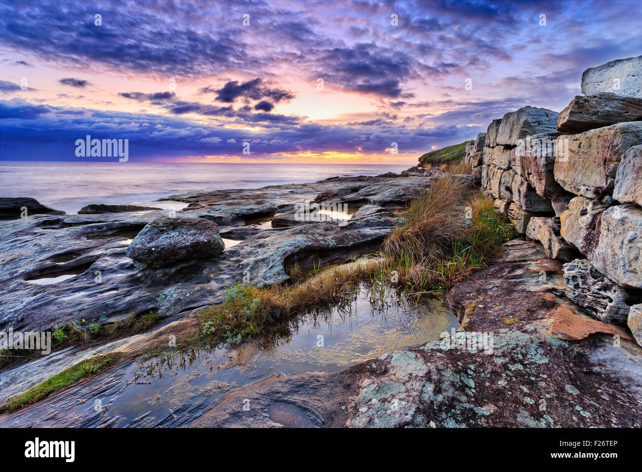 Seascape vista la natura nei pressi di Maroubra Beach a Sydney con pietra naturale posati a parete paesaggistica di marcatura bushwalking via di sunrise Foto Stock