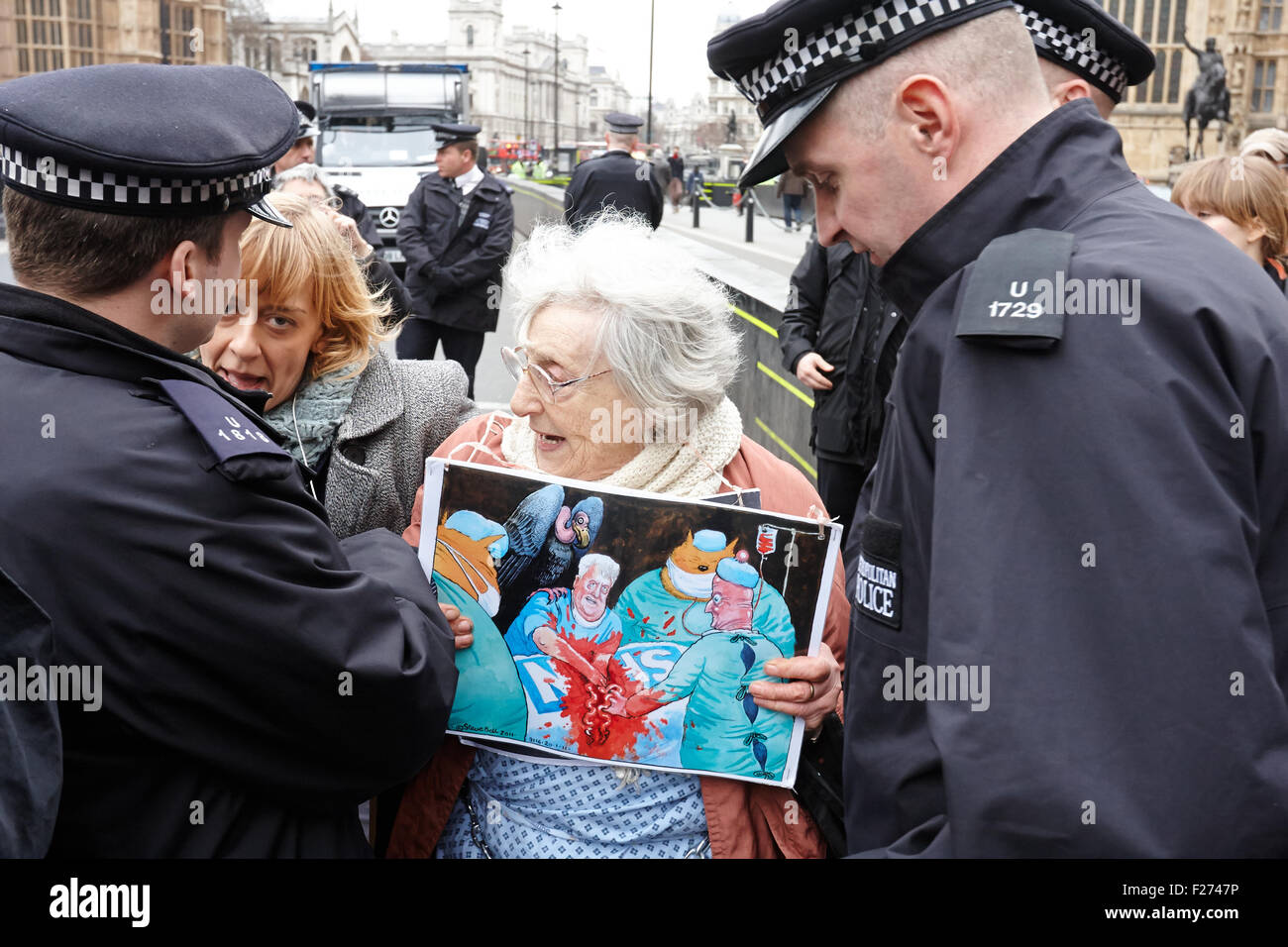 Manifestanti attirare l' attenzione della polizia mentre protestando contro la NHS la riduzione di finanziamenti al di fuori della sede del parlamento di Londra Foto Stock