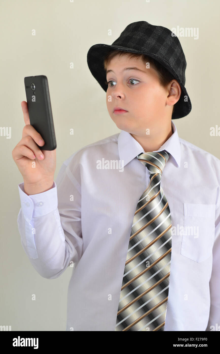 Teen boy con sorpresa guarda a un telefono cellulare Foto Stock