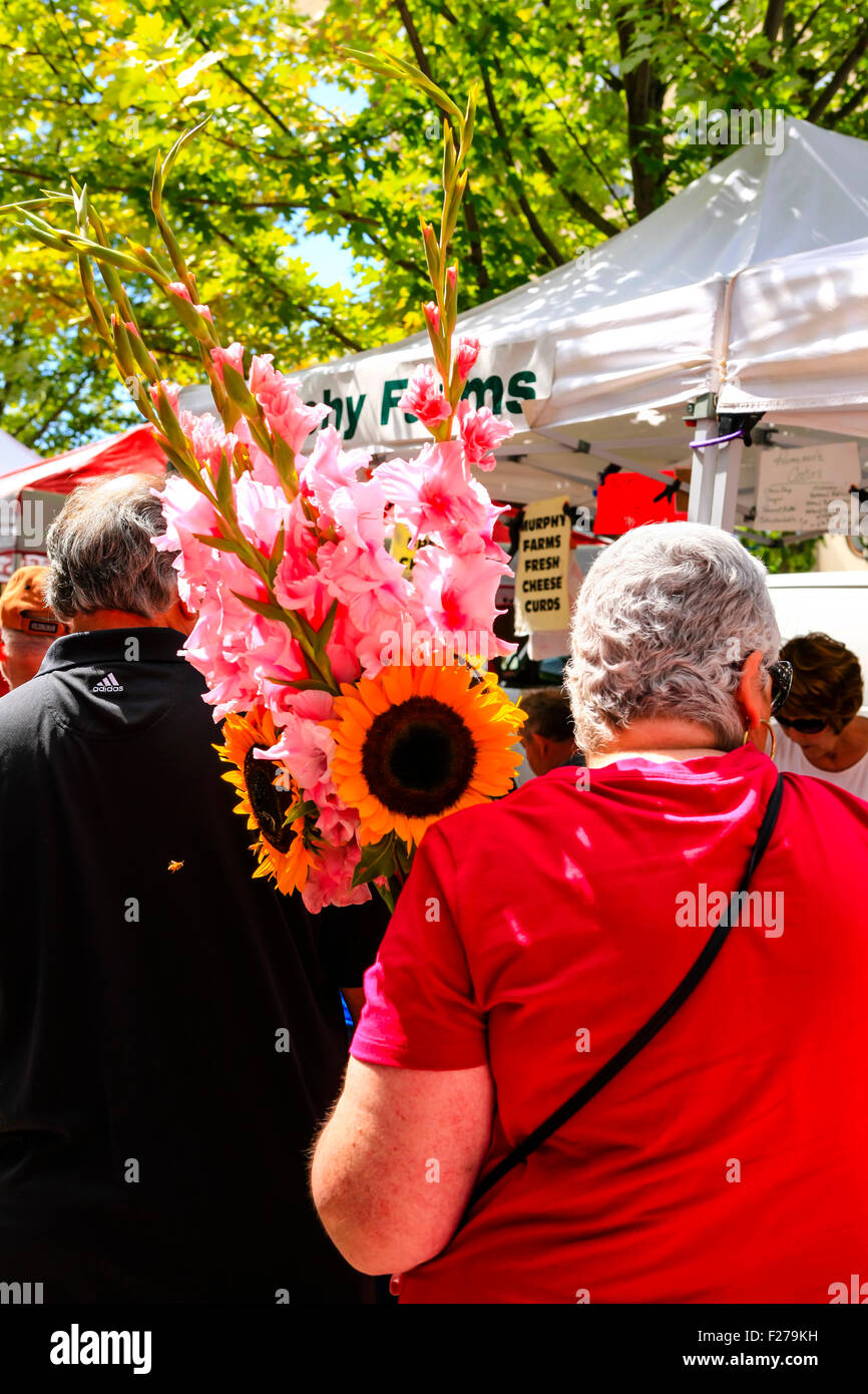 Donna che trasportano gladioli e girasoli ha acquistato presso il sabato Mercato degli Agricoltori in Madison WI Foto Stock