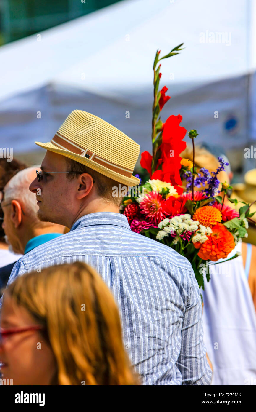 Uomo che indossa un cappello estivo porta un mazzo di fiori ha acquistato presso il mercato del sabato in Madison WI Foto Stock