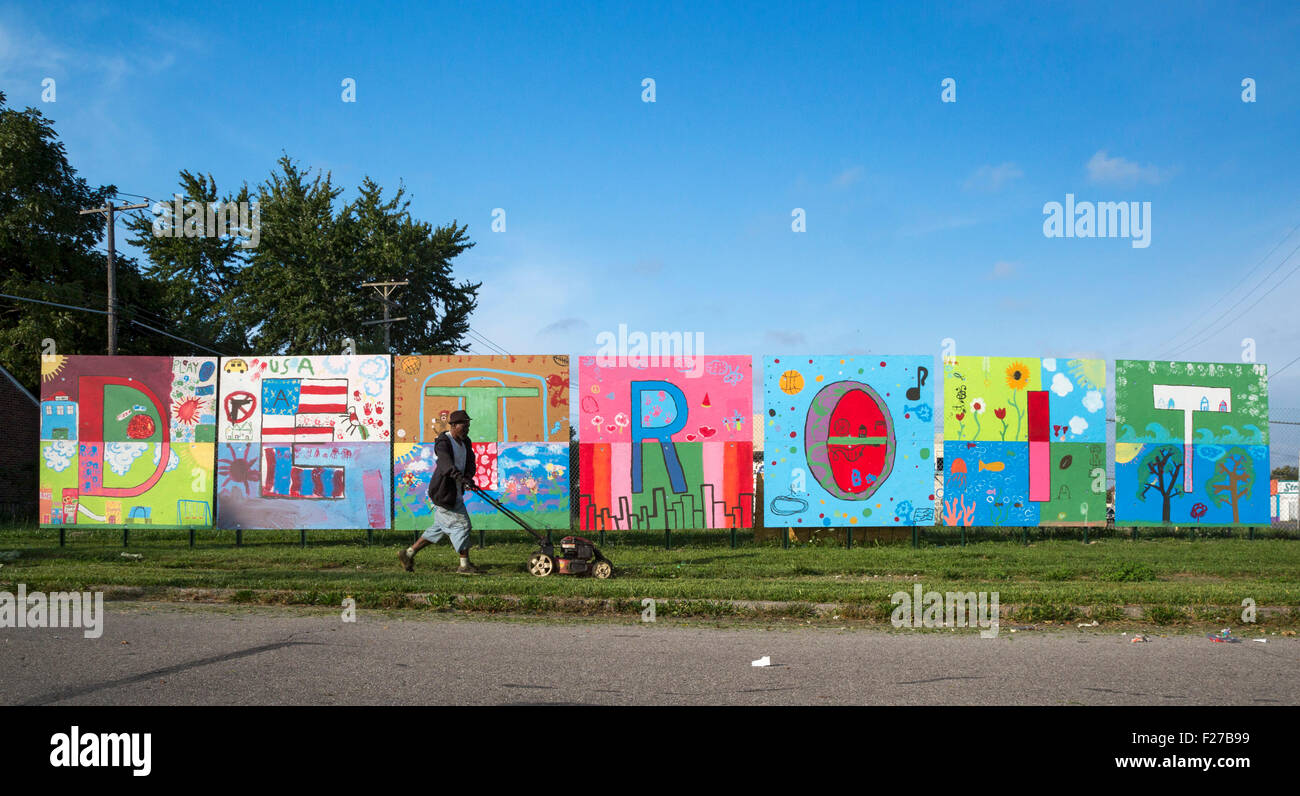 Detroit, Michigan - un uomo mows l'erba davanti a un dipinto compitazione 'Detroit' sulla città e sul suo lato orientale. Foto Stock