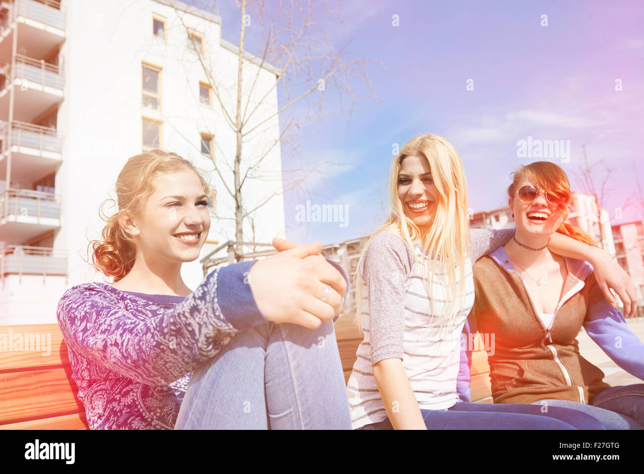 Tre amici seduti su una panchina in un parco giochi, Monaco di Baviera, Germania Foto Stock