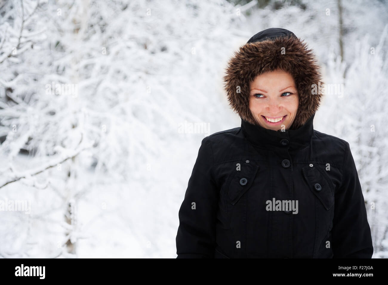 Allegro Caucasian giovane donna in caso di neve nel parco con coperte di neve alberi, spazio di copia Foto Stock