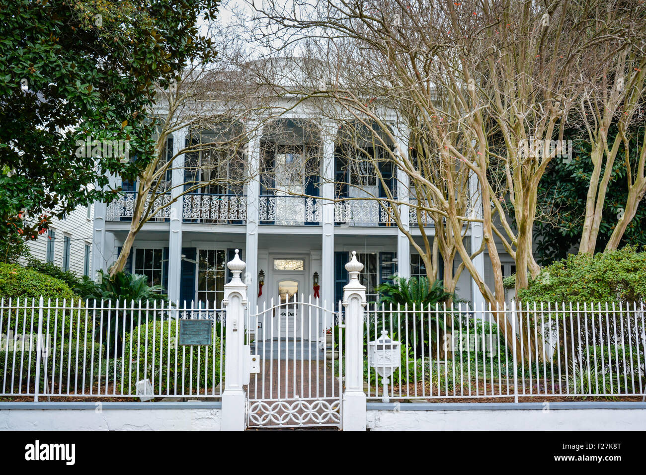 Un maestoso palazzo con colonne bianche e lacy balcone in ferro dietro cancelli nel Garden District di New Orleans, LA Foto Stock