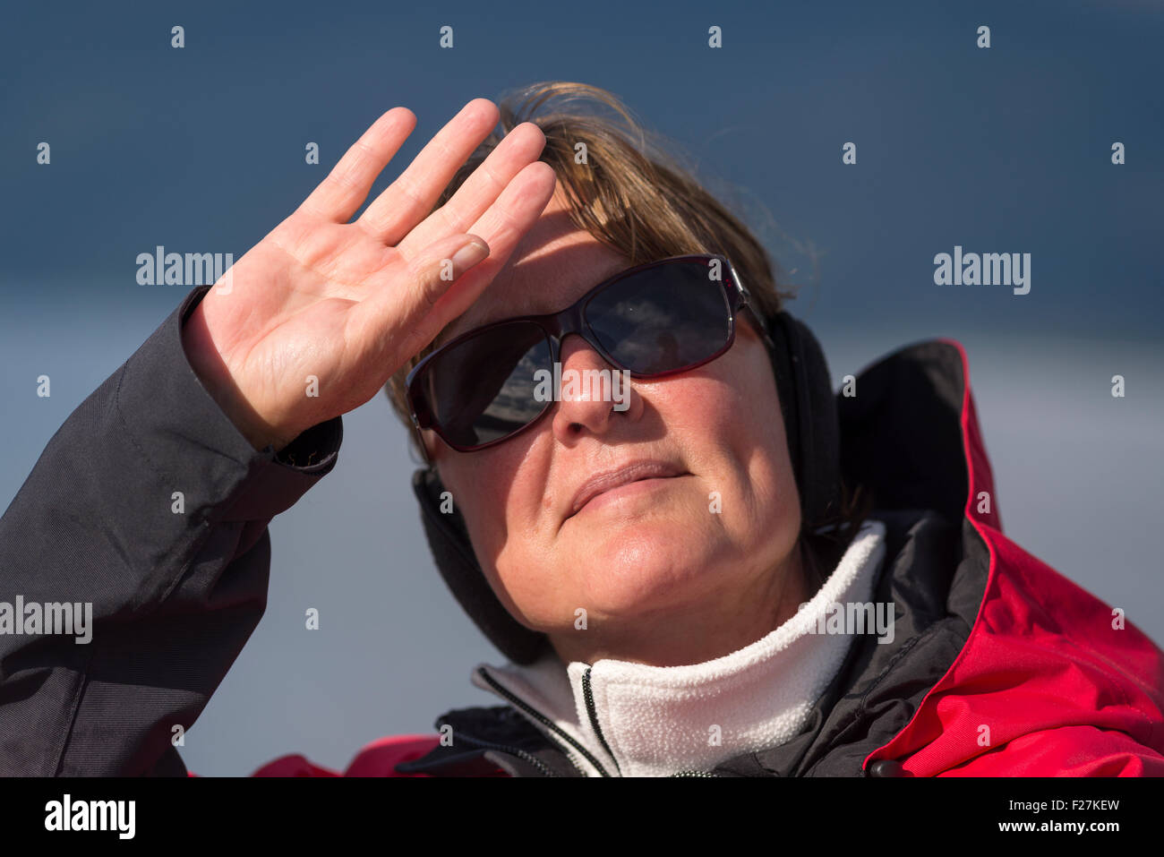 La donna la schermatura del sole dai suoi occhi come lei guarda fuori. Foto Stock