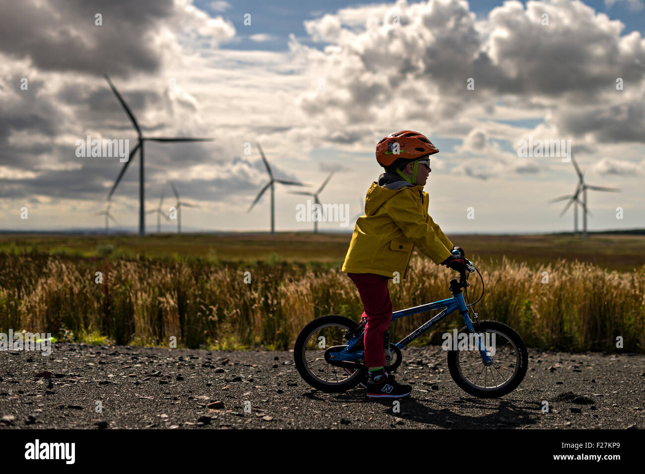 EAGLESHAM, Scozia - 28 agosto: una vista generale di un giovane bambino maschio escursioni in bicicletta su una pista ciclabile tra le turbine eoliche sulla Scottish Foto Stock