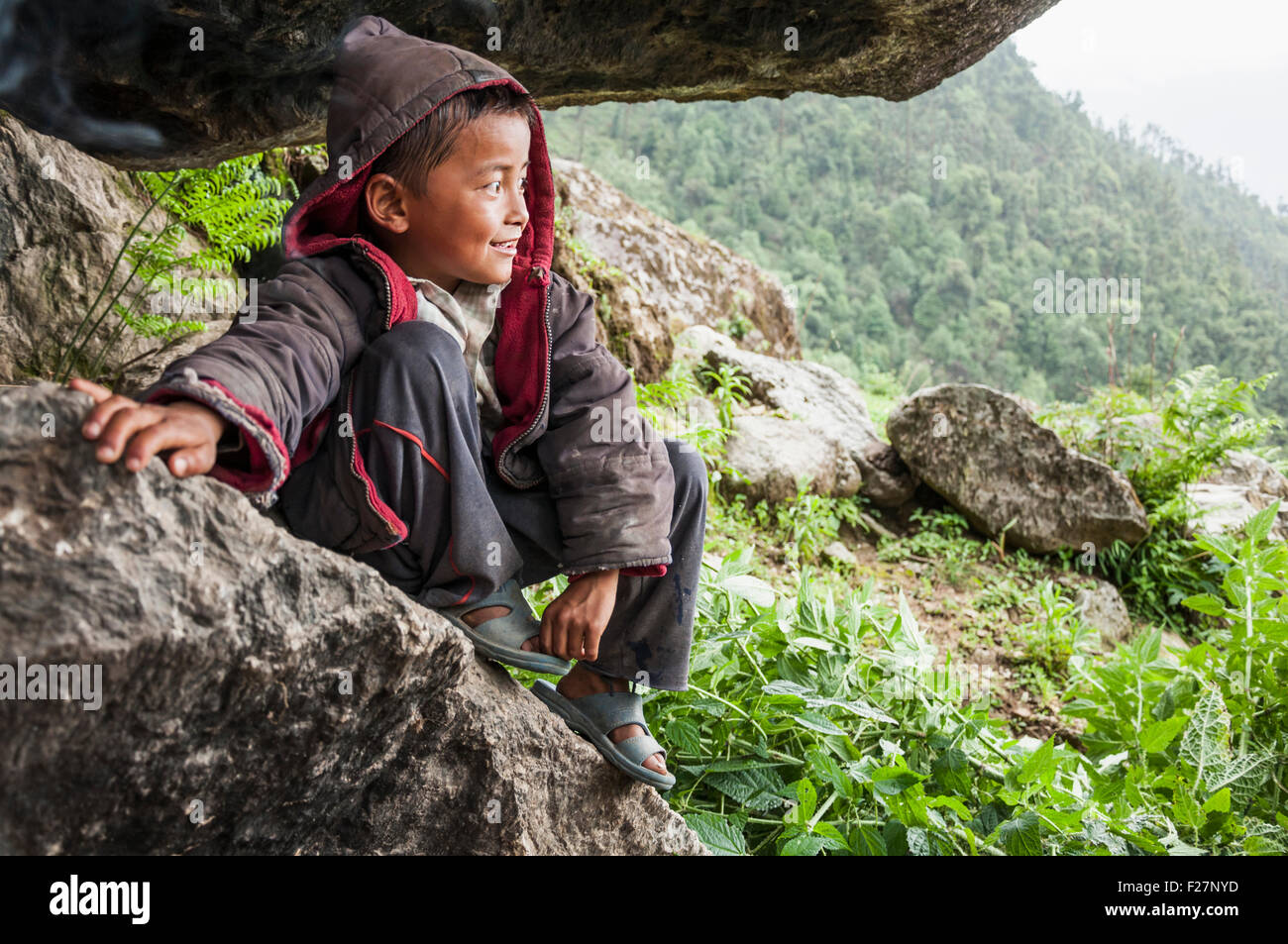 Ragazzo seduto sulla roccia e guardando a Mountain View, Nepal Foto Stock