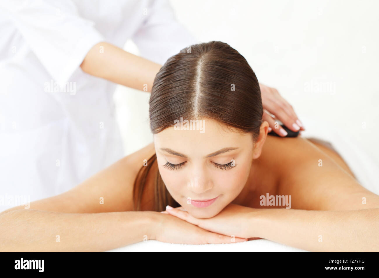 Giovane bella donna in spa come ottenere un massaggio con pietre calde Foto Stock