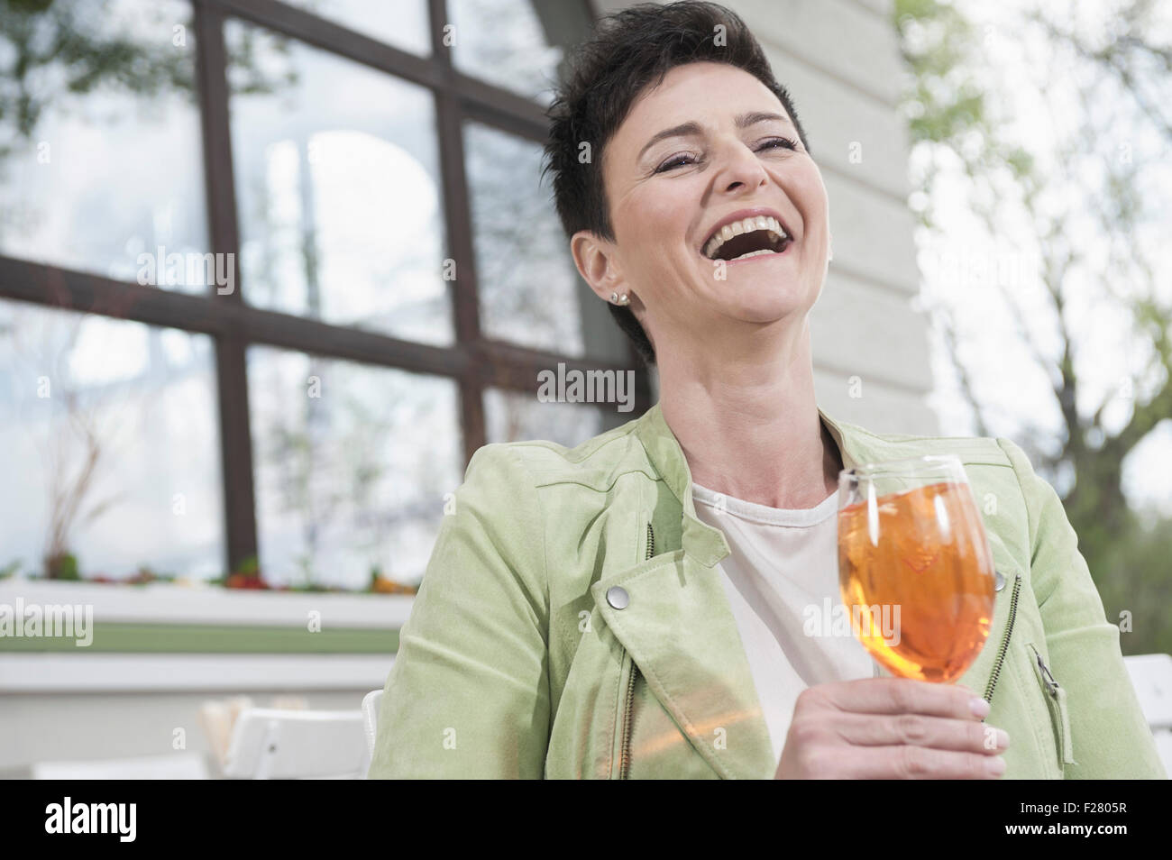 Donna matura a ridere con aperol spritzat al cafè sul marciapiede, Baviera, Germania Foto Stock
