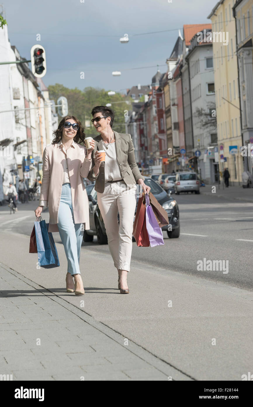 Due donne mature di shopping in città con caffè, Baviera, Germania Foto Stock