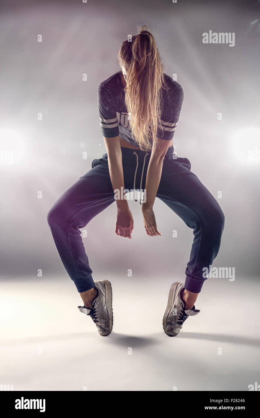 Femmina di Hip Hop ballerino in punta la posizione di punta con i suoi capelli che copre il volto contro la parete marrone Background in Studio. Foto Stock