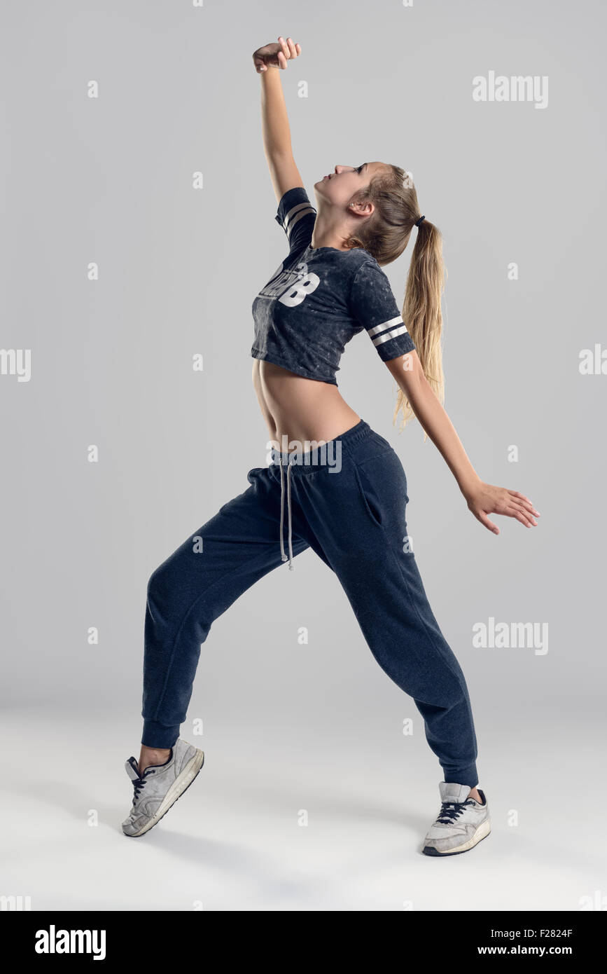 A piena lunghezza shot di una giovane donna di Hip Hop Ballerina in punta di piedi posizione contro il muro grigio Sfondo. Foto Stock