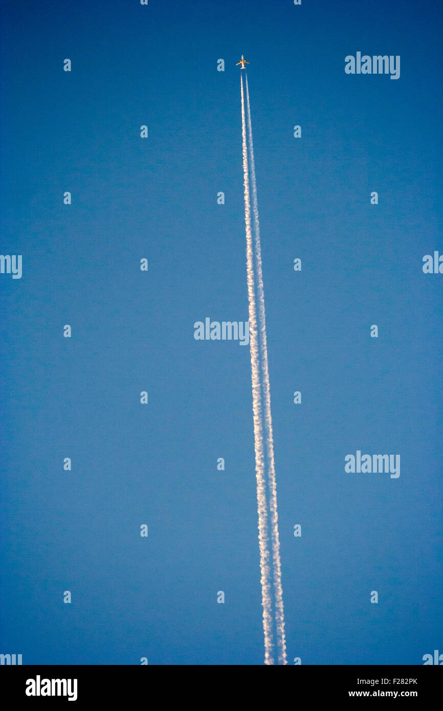 High flying piano lasciando contrail appena dopo il tramonto in chiaro inizio del cielo della sera. Glinting soleggiato sul piano. Foto Stock