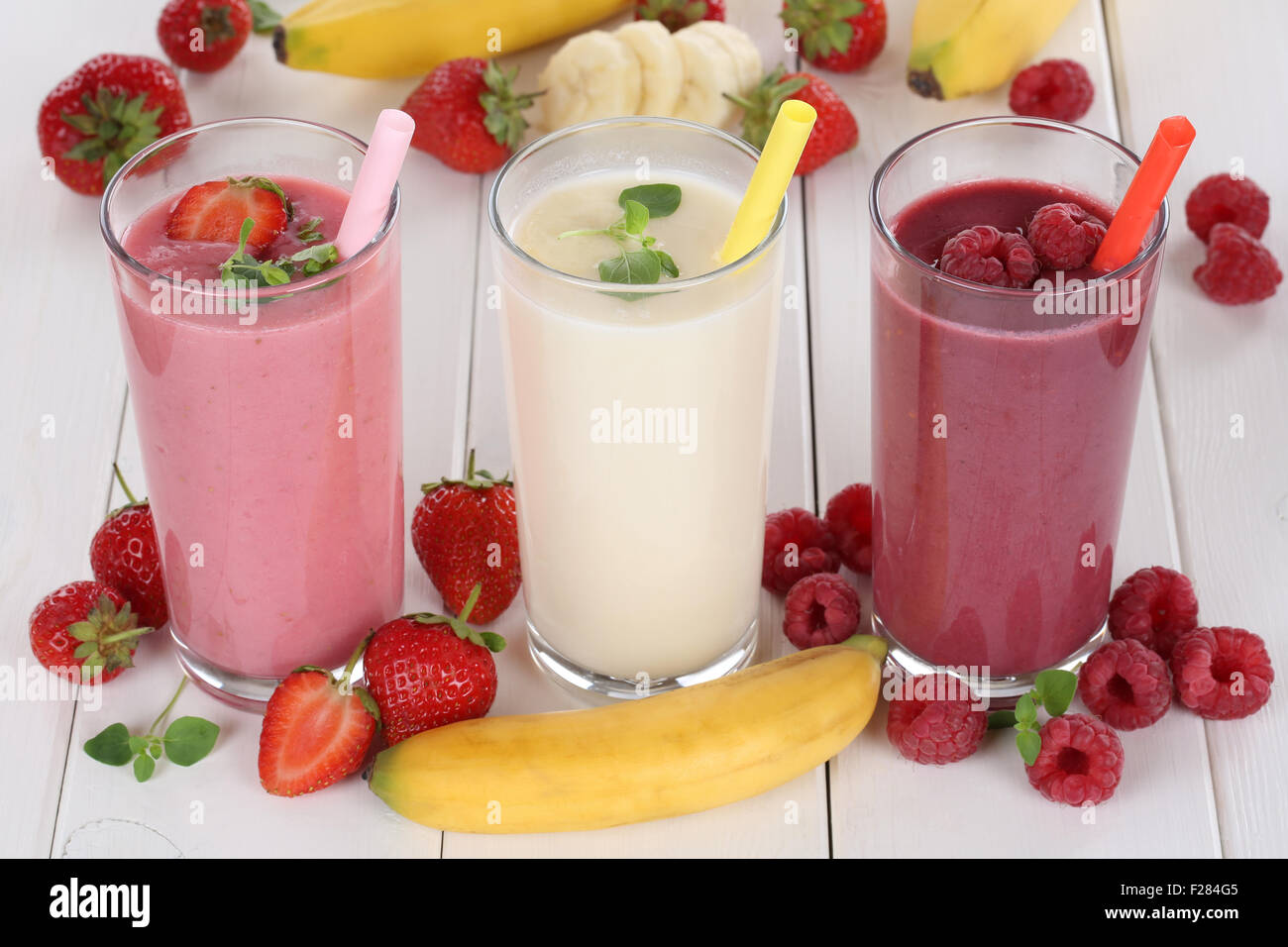 Frullato di succo di frutta con frutti come fragole, lamponi e banana in vetro Foto Stock