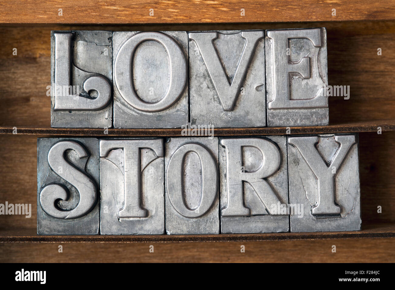 Una storia di amore frase composta da metallico tipo di stampa in rilievo sul vassoio in legno Foto Stock