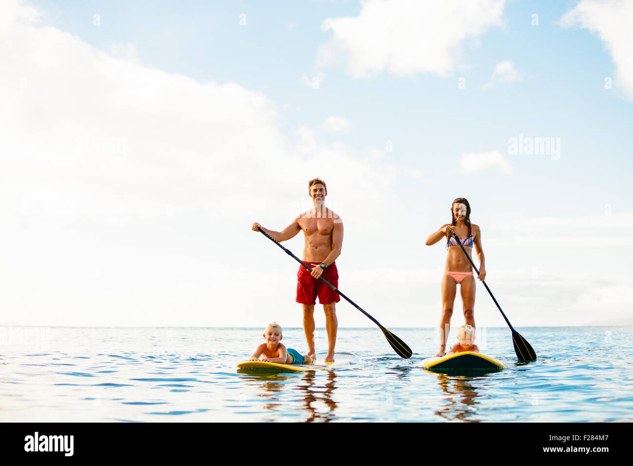 Famiglia avente Fun Stand Up Paddling insieme nell'oceano sulla splendida mattina di sole Foto Stock