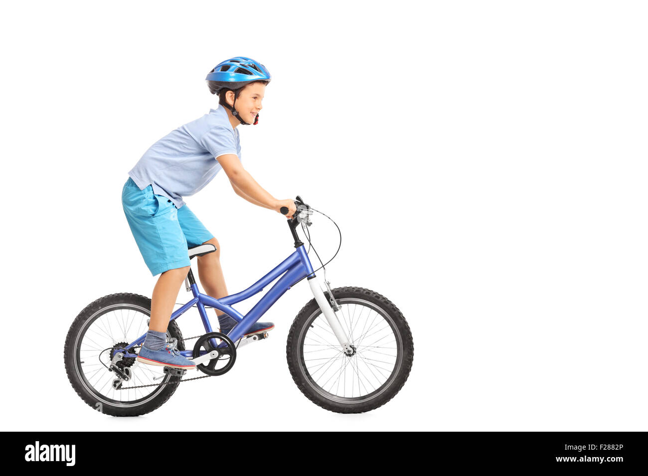 Colpo di profilo di un ragazzino con casco blu a cavallo di un piccolo blu bike isolati su sfondo bianco Foto Stock