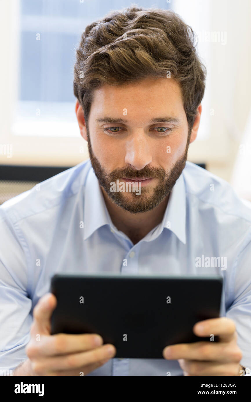 Business Casual Uomo al lavoro su tablet PC in ufficio Foto Stock