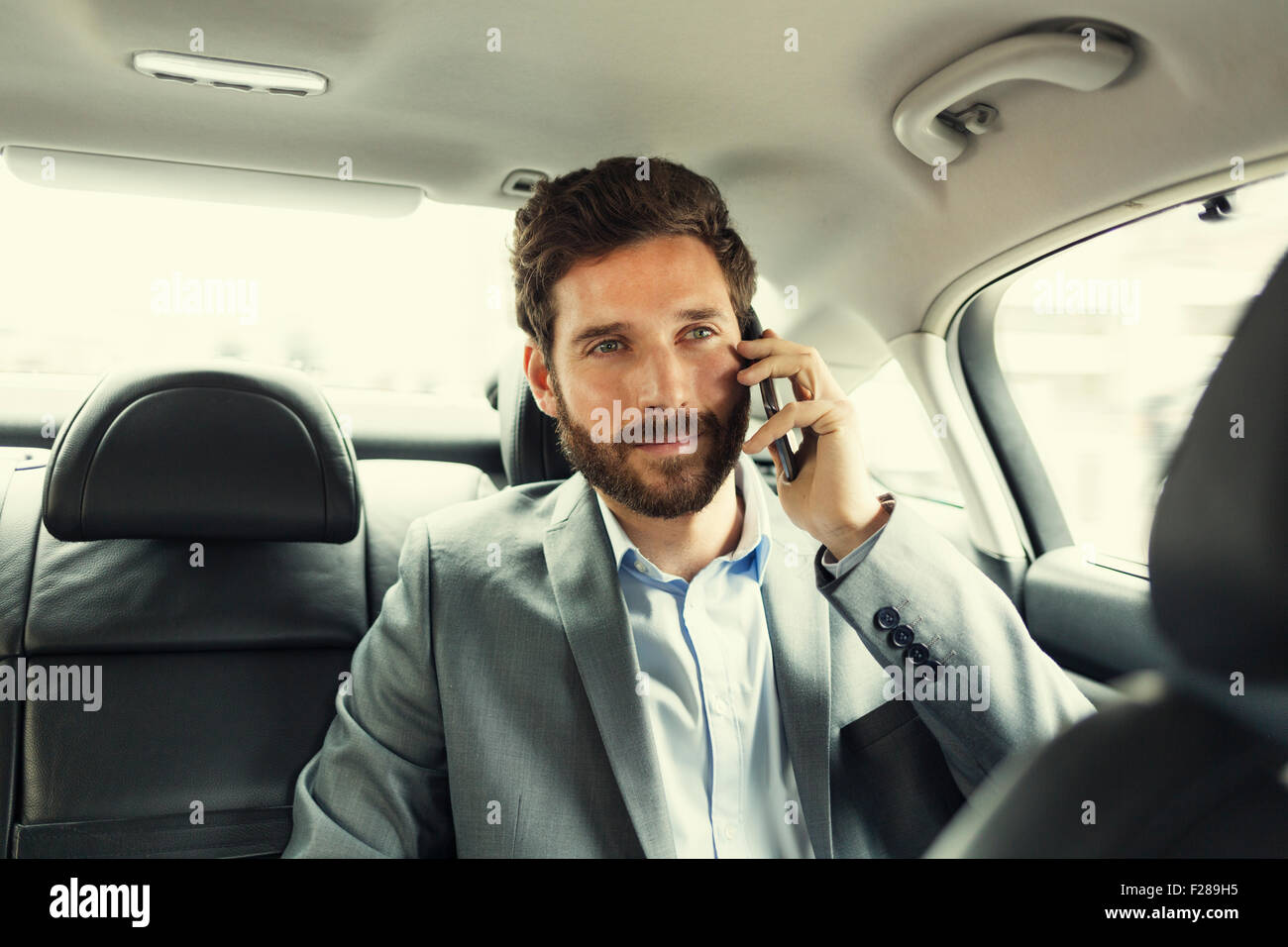 Business Casual Uomo sul telefono cellulare nella parte posteriore della vettura Foto Stock