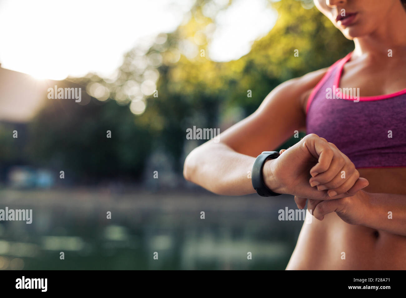 La donna con l'impostazione del fitness orologio smart per l'esecuzione. Sportive controllo guarda il dispositivo. Foto Stock