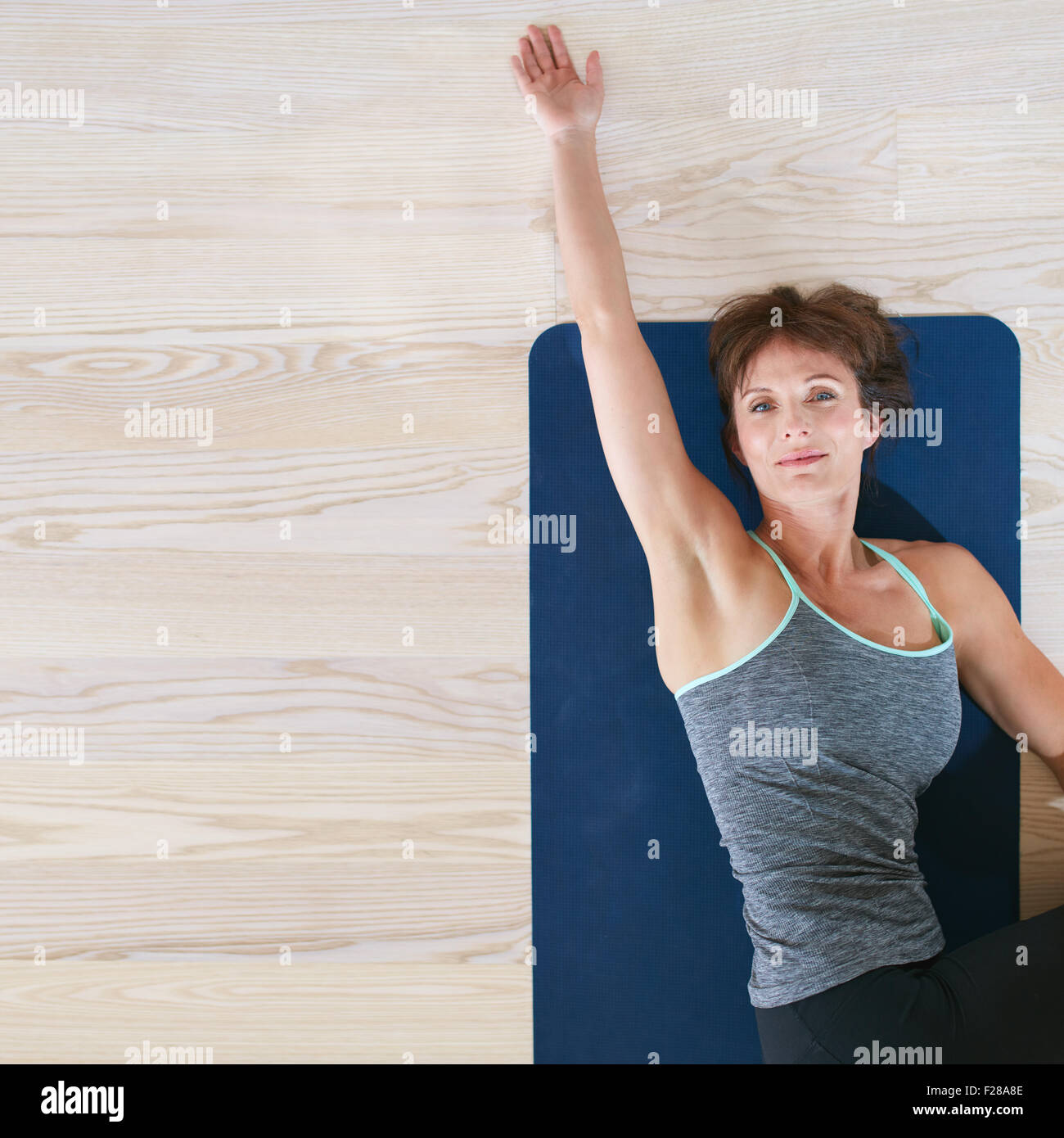 Vista superiore della donna sdraiata e stretching sull esercizio mat. Femmina su piano torcendo il suo corpo e il suo allungamento una mano. Foto Stock