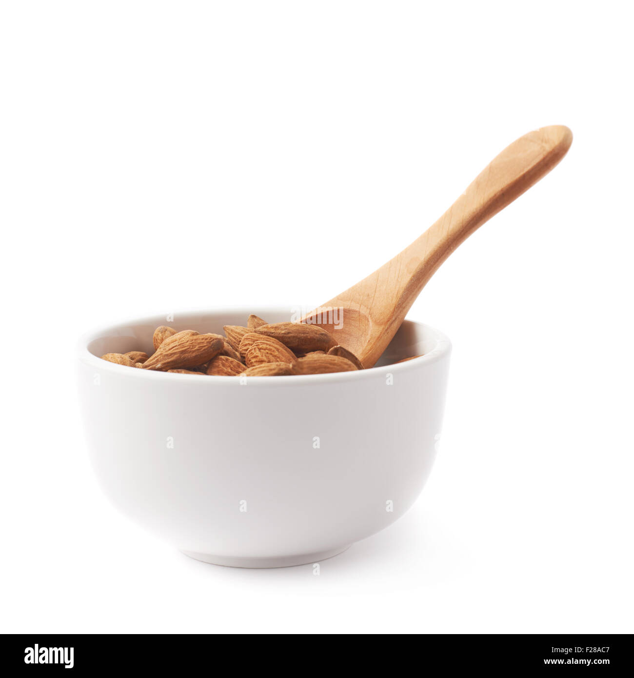 Ceramic White ciotola piena di semi di mandorle e in legno misurino, composizione isolata su sfondo bianco Foto Stock