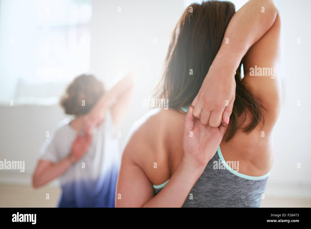 Vista posteriore di montare donna gomukhasana facendo yoga in classe. Femmina Fitness tenendo le mani dietro la schiena e stretching. Tricipiti un Foto Stock