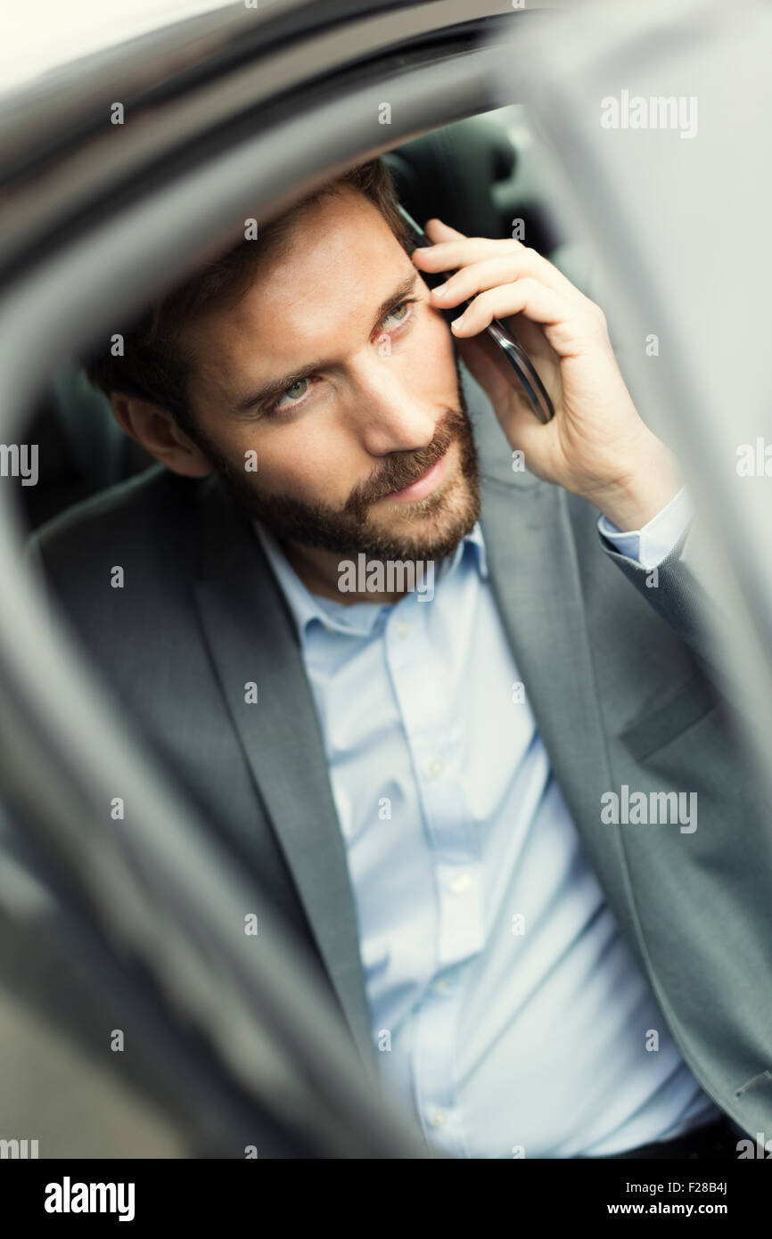 Business Casual Uomo sul telefono cellulare nella parte posteriore della vettura Foto Stock