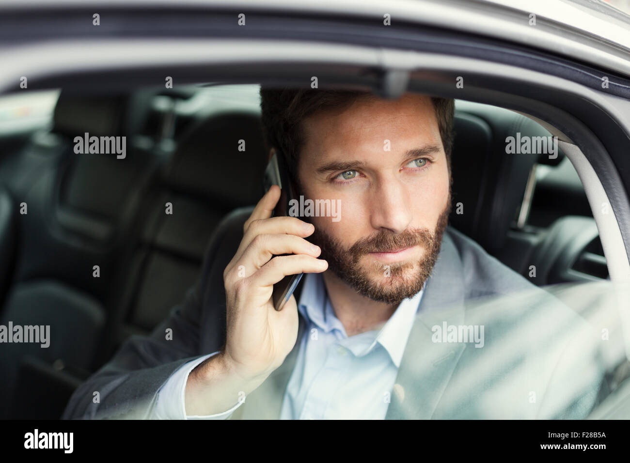 Business Casual Uomo sul telefono cellulare nella parte posteriore della vettura Foto Stock