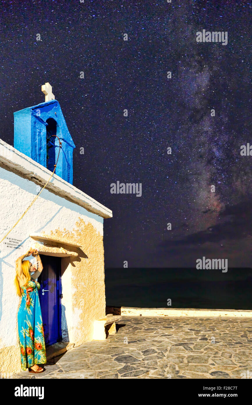 Una donna di fronte a una cappella Greca sotto la Via Lattea Foto Stock
