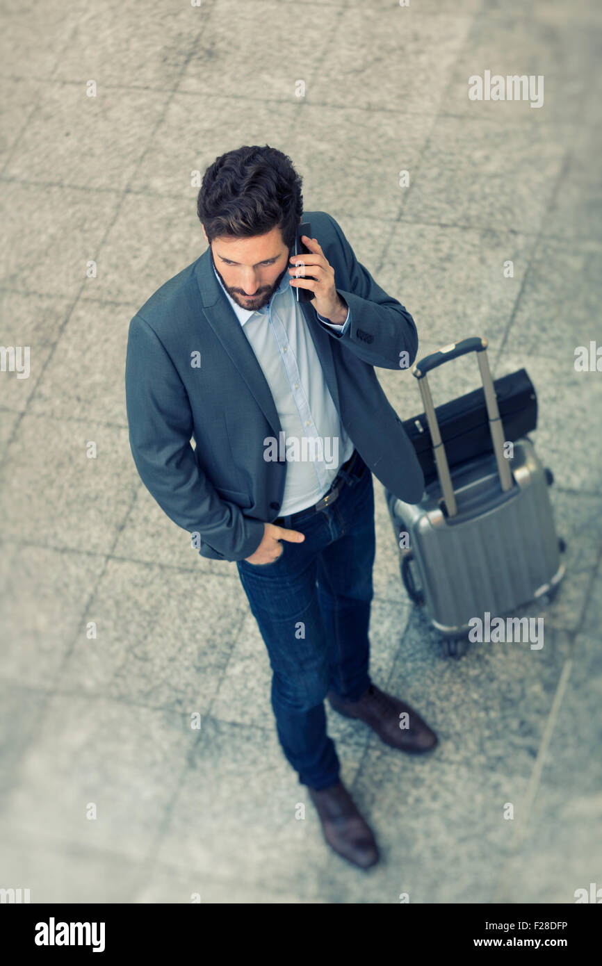 Moderno business casual uomo sul telefono cellulare in hall aeroporto. Vista superiore Foto Stock